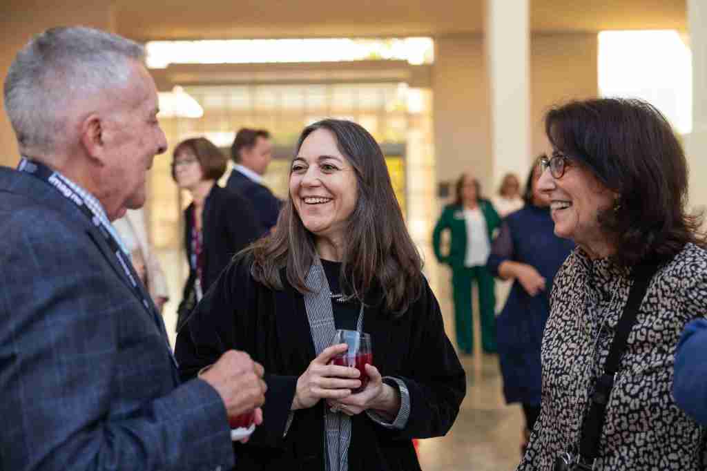 A group of three people smile at one another