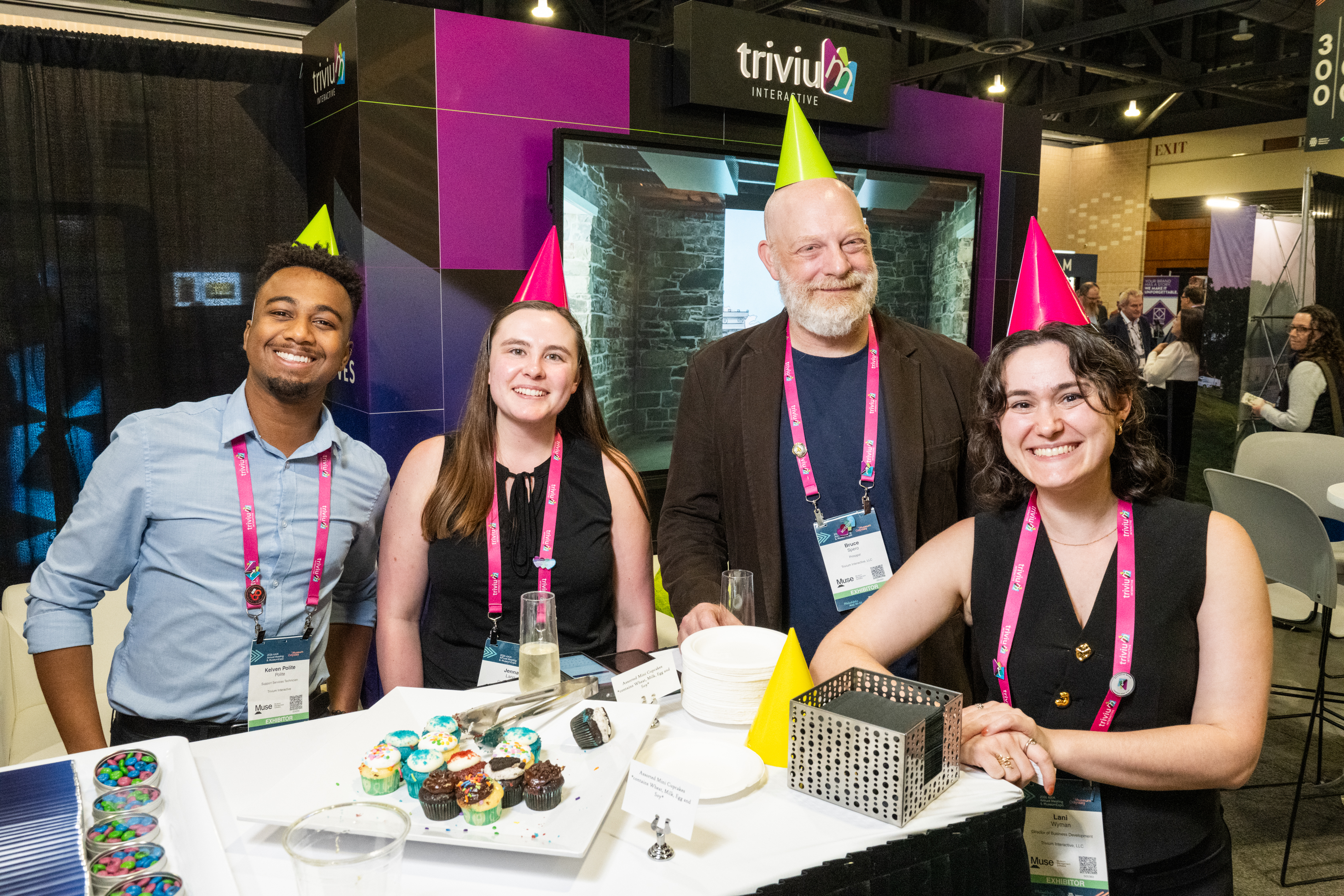 A group of exhibitors smiling in birthday hats